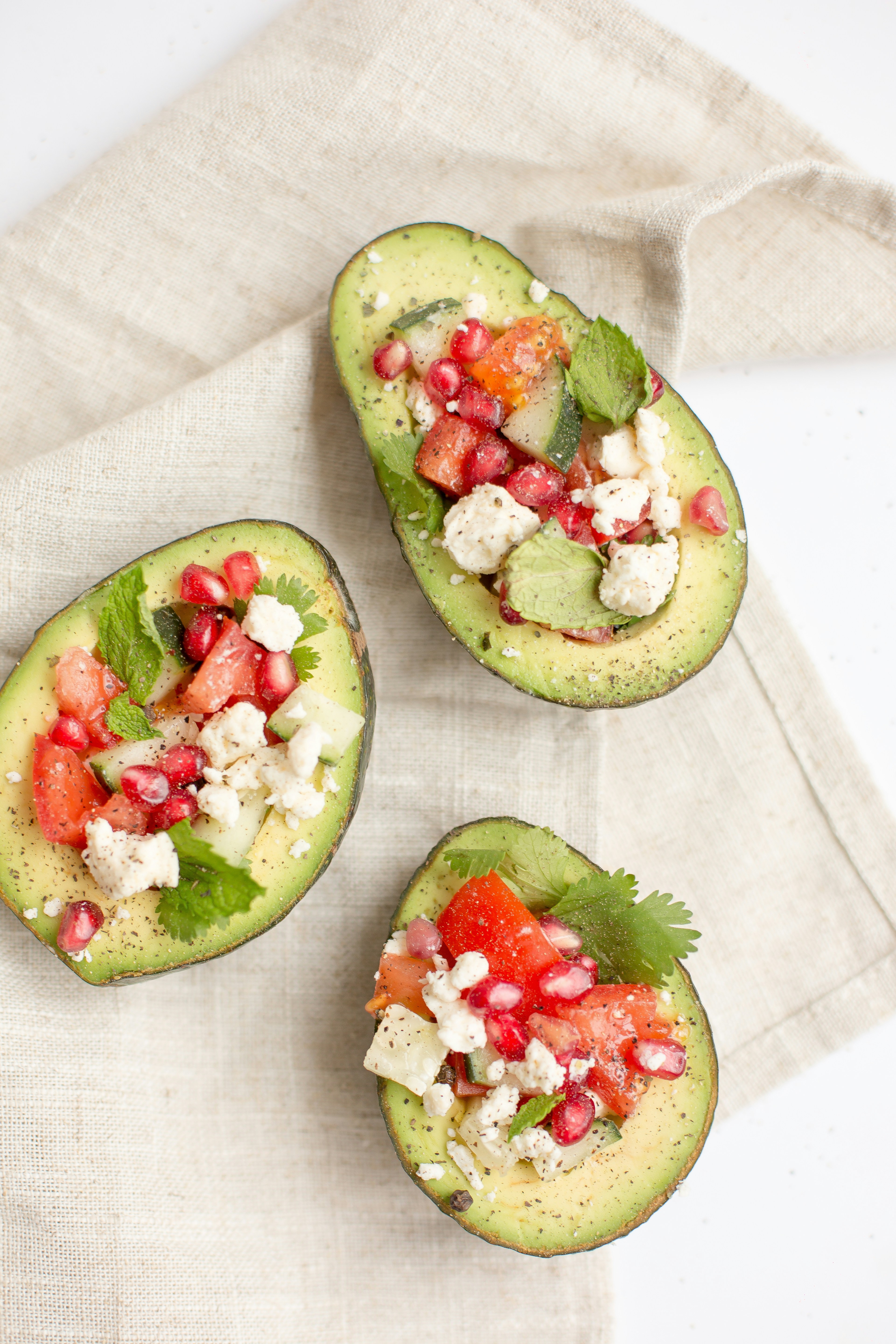 Avocados loaded with tomatoes, cucumbers, and feta cheese with a green garnish